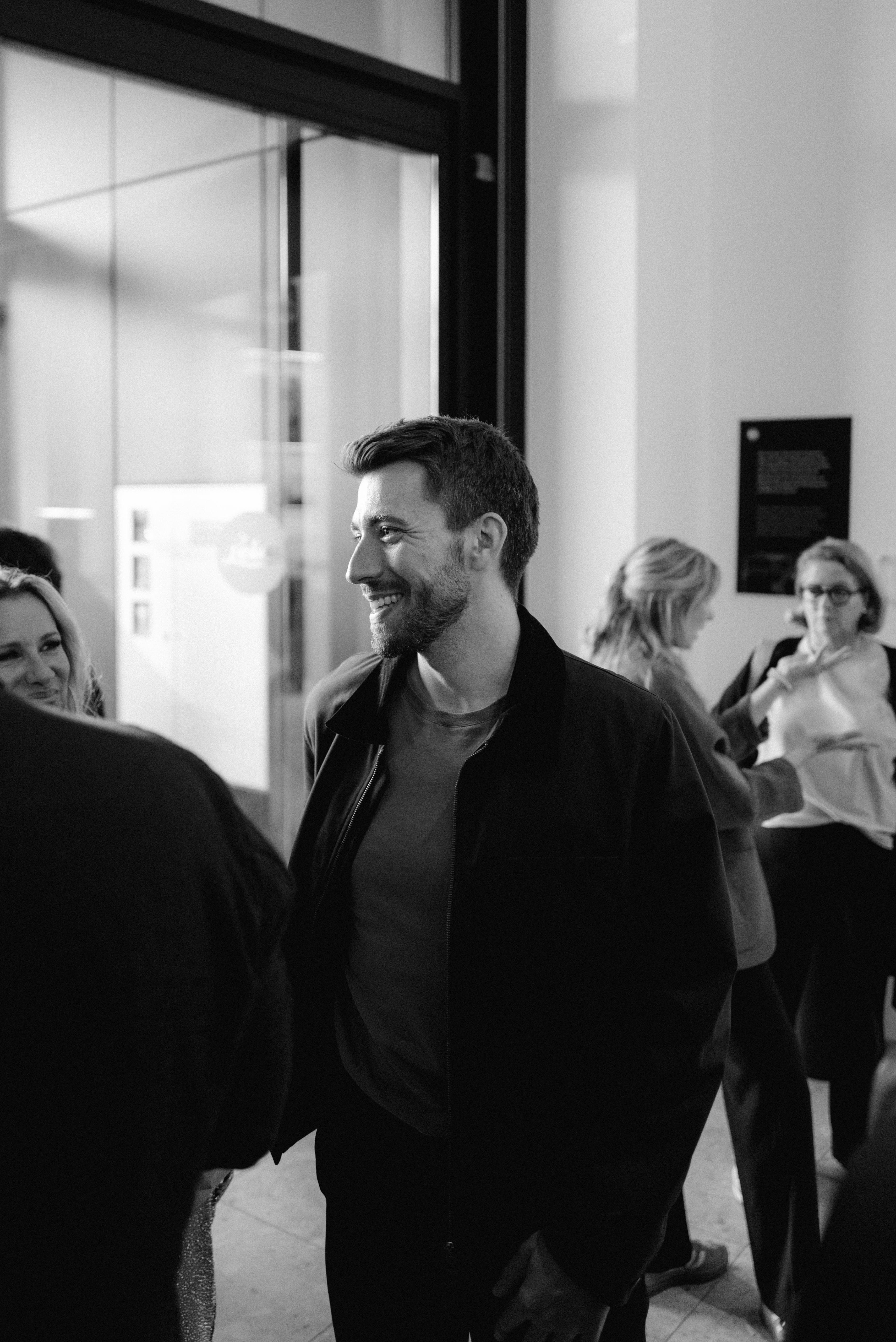 Gast in dunkler Jacke im Gespräch beim Empfang im Museumsfoyer, schwarzweiß