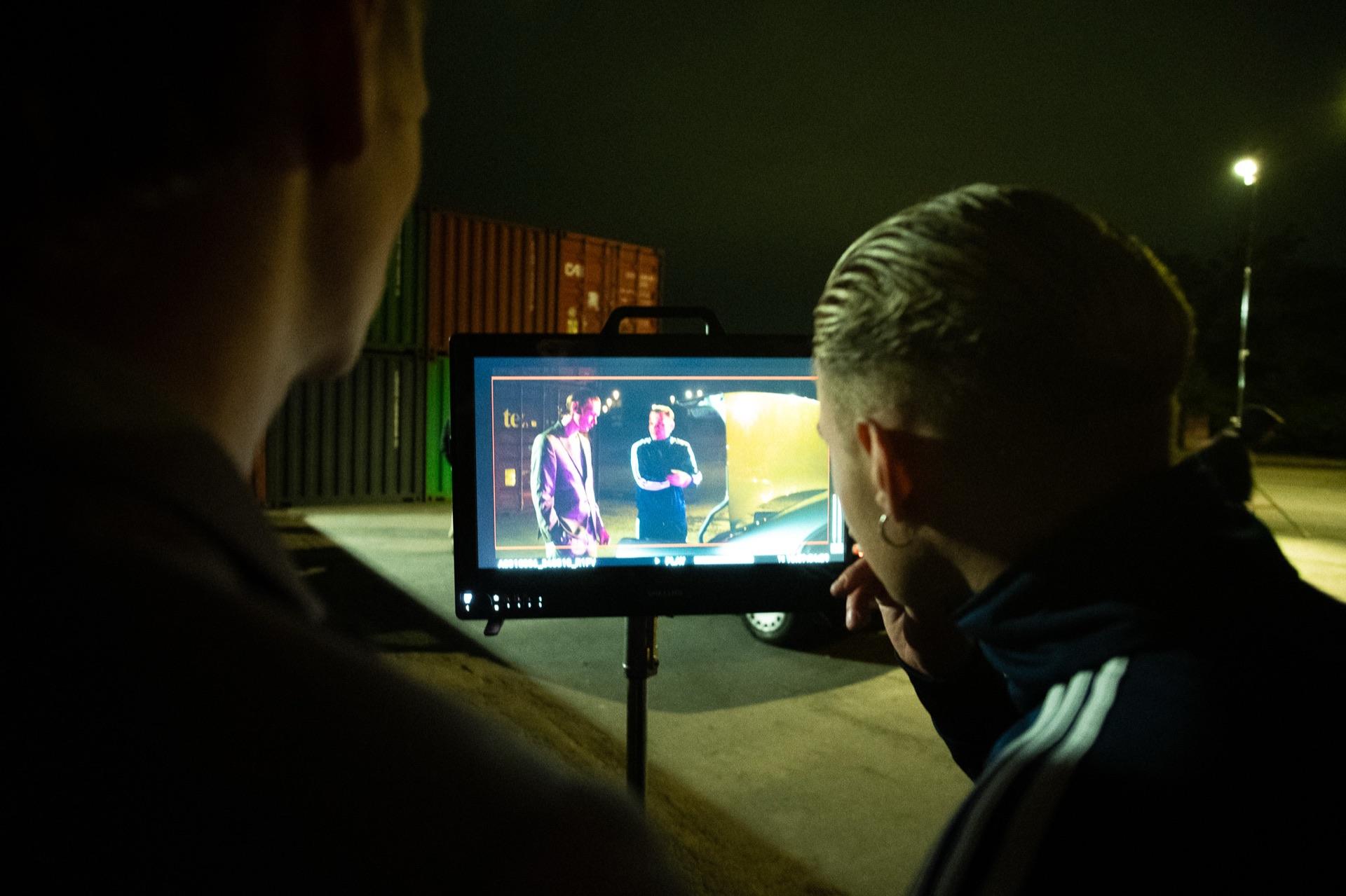 Behind the Scenes: zwei aus der Crew prüfen die Einstellung am Monitor, im Display die beiden Darsteller