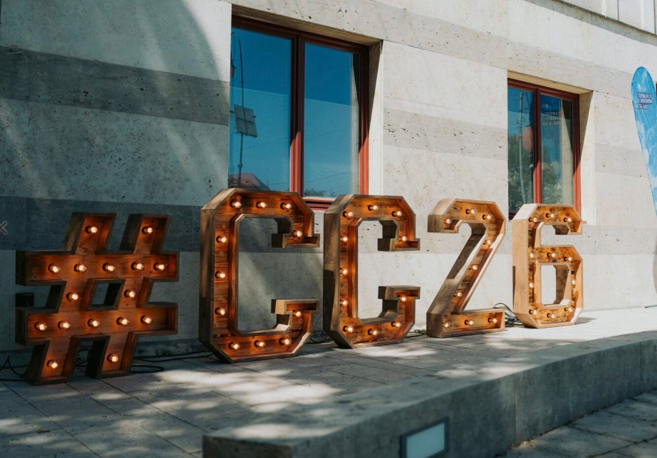 Große beleuchtete Holzbuchstaben mit dem Schriftzug Hashtag CC26 vor der Fassade des Amerikahauses
