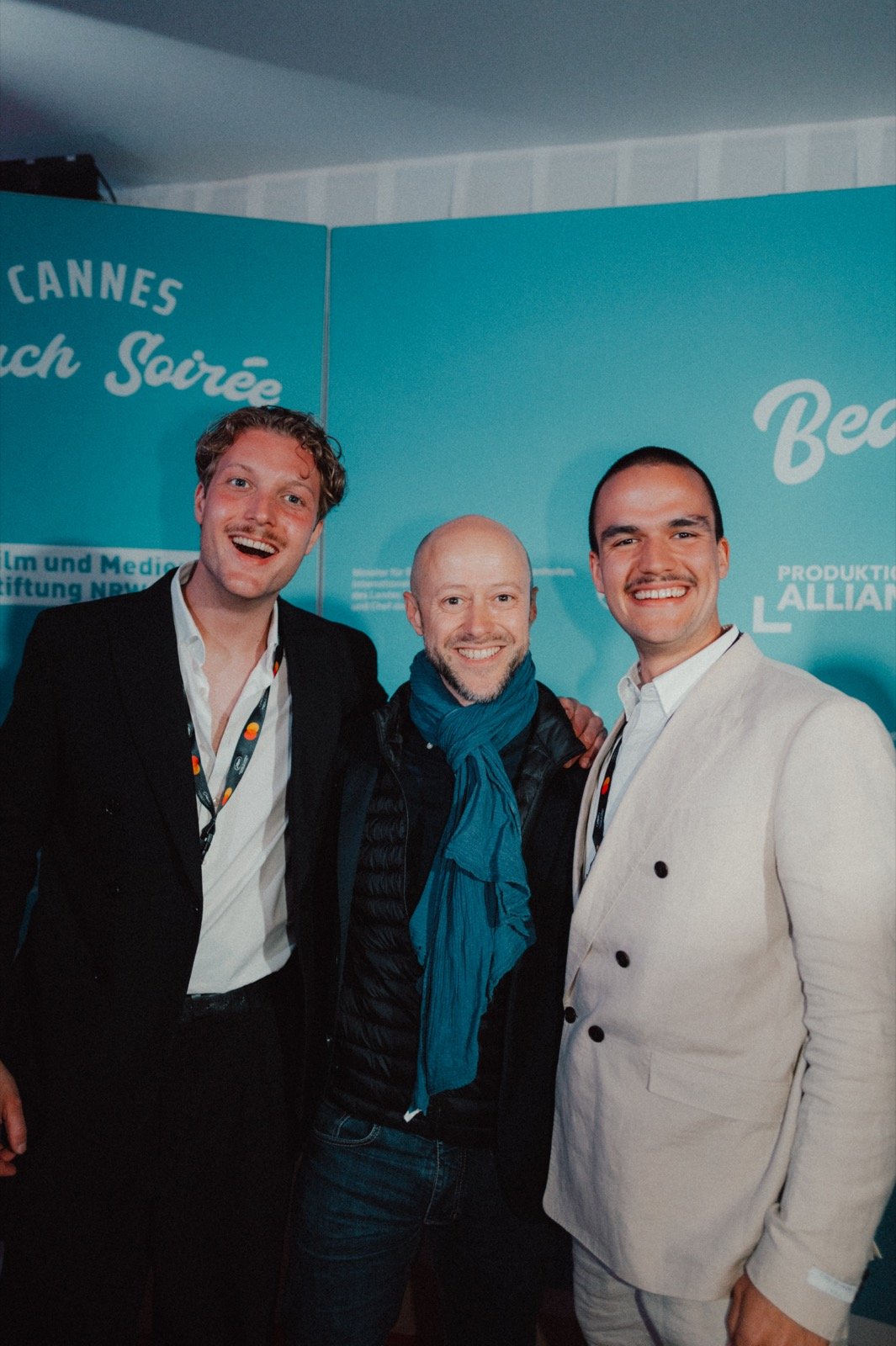 Jakob Hermann Hähner, Fabian Gasmia und Johannes Fielers beim Empfang vor einer Cannes-Fotowand