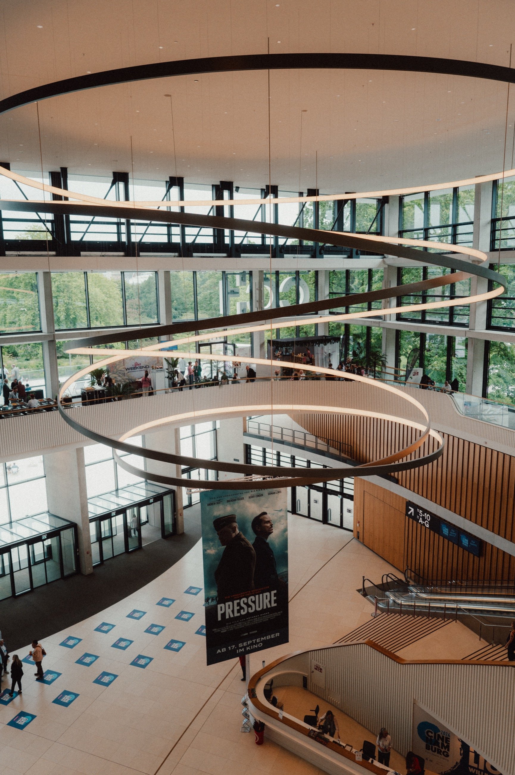 Blick von oben ins Foyer des CCH, geschwungene Lichtringe unter der Decke, darunter ein Filmplakat
