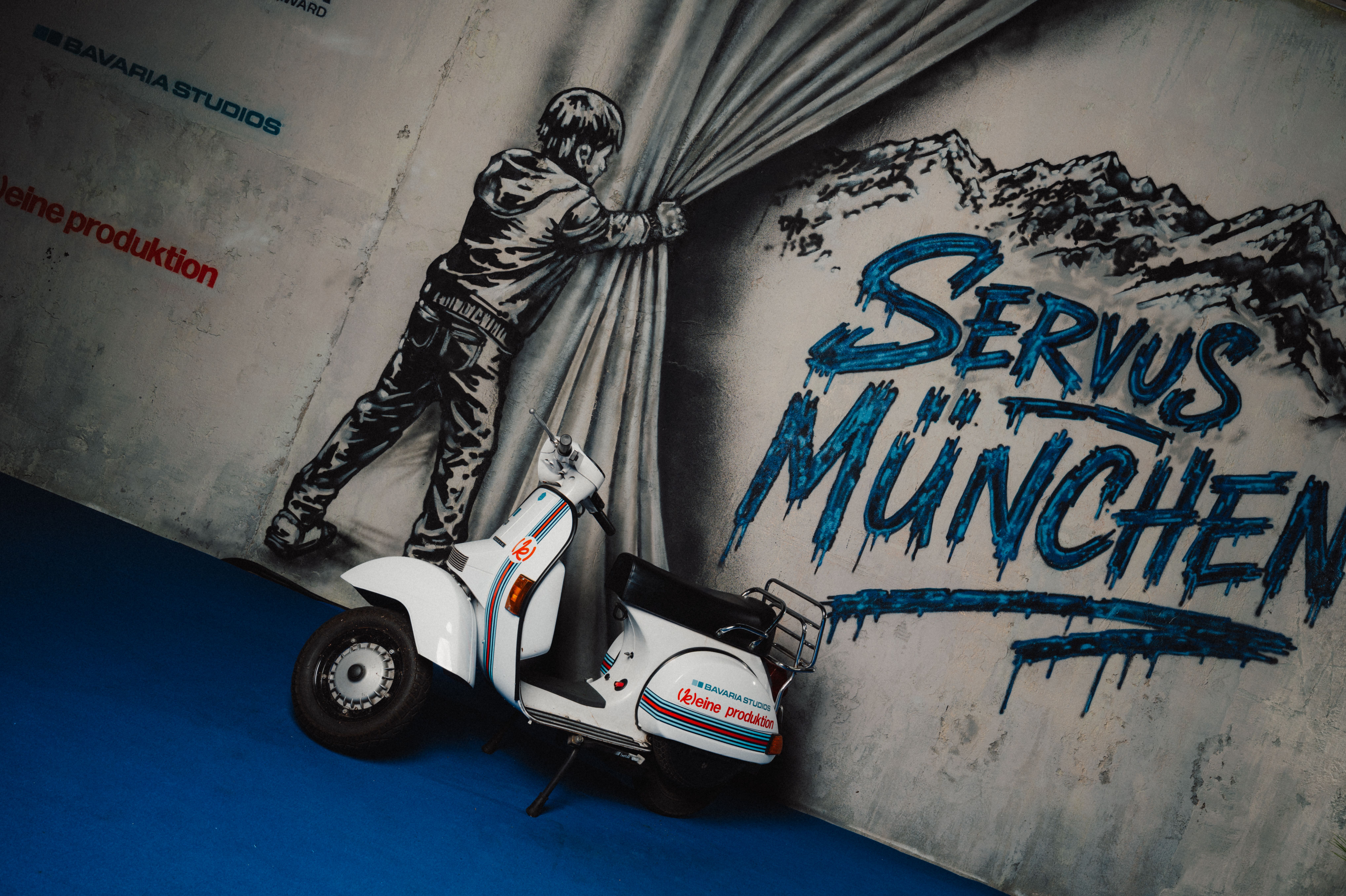 Die gebrandete Vespa von [k]eine produktion vor dem Servus München Wandbild in den Bavaria Studios