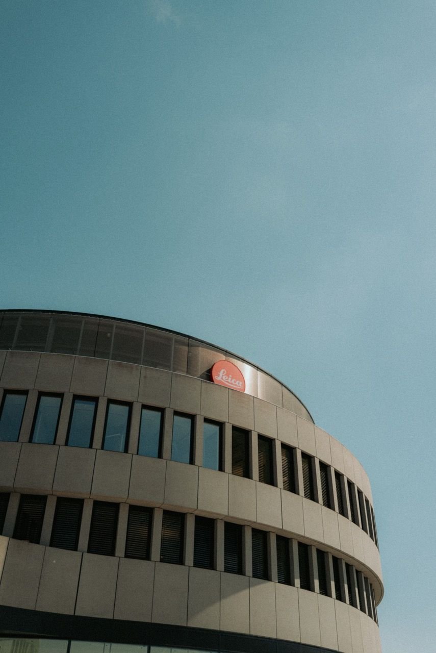 Runder Bau des Leitz-Parks mit rotem Leica-Punkt an der oberen Kante, darüber blauer Himmel