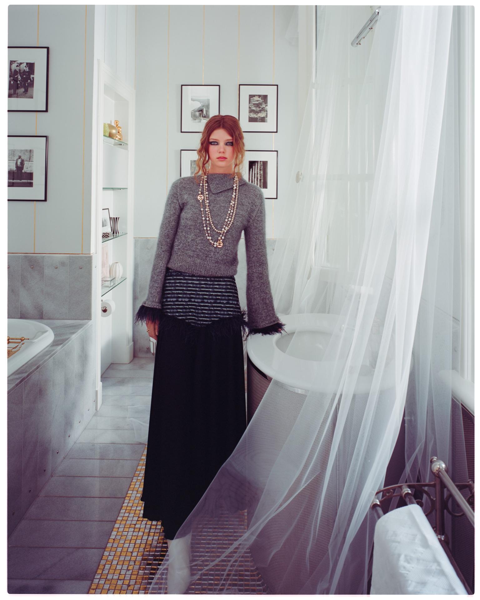 Modell in langem Kleid an einem Fenster mit wehendem Vorhang im Salon