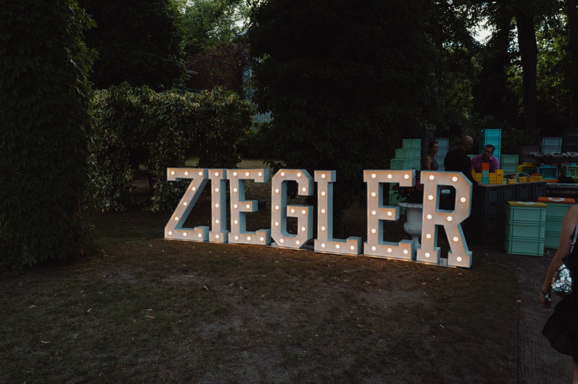 Beleuchteter Schriftzug „Ziegler“ im Garten des Schlosshotels Berlin bei Dämmerung